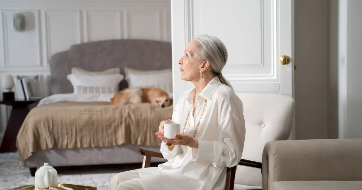 An elderly woman with a hound dog sitting on her porch, looking at each other affectionately